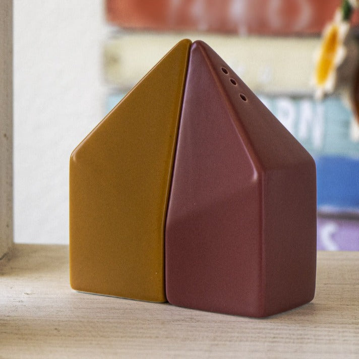 A pair of ceramic salt and pepper shakers designed to resemble a house, with a yellowish and red color scheme.