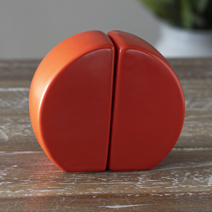 A pair of red ceramic salt and pepper shakers designed in the shape of a moon gate.