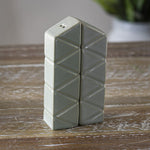 Ceramic salt and pepper shakers with a geometric pattern, presented on a wooden surface.