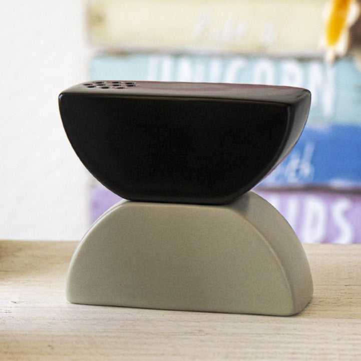 A black and white ceramic salt or pepper shaker designed to resemble stacked stones.