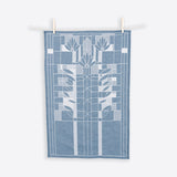 A blue and white cotton tea towel with a geometric waterlilies pattern hanging on two wooden clothespins against a white background.
