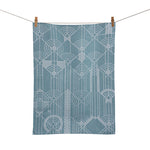 A blue jacquard tea towel with a geometric pattern hanging on a clothesline.