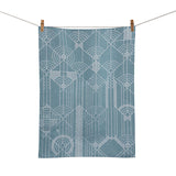 A blue jacquard tea towel with a geometric pattern hanging on a clothesline.