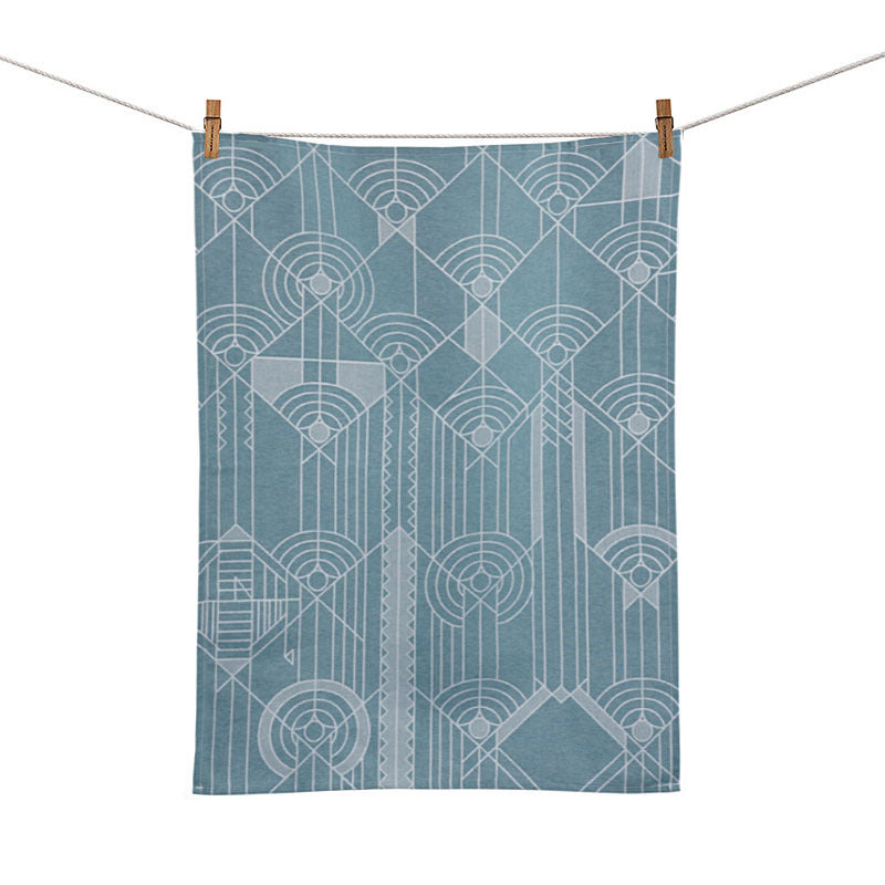 A blue jacquard tea towel with a geometric pattern hanging on a clothesline.