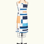 An apron featuring a geometric pattern with blue, white, and orange colors, displayed on a mannequin.