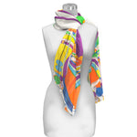 A silky sheer long scarf with a multicolored geometric pattern displayed on a mannequin.