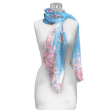 A silky sheer scarf with a cherry blossom design, displayed on a mannequin.