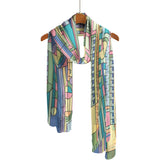 Colorful scarf with geometric pattern on a wooden hanger against a white background