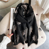 An oblong scarf with a gingko leaves pattern in black and beige colors, displayed on a neutral background.