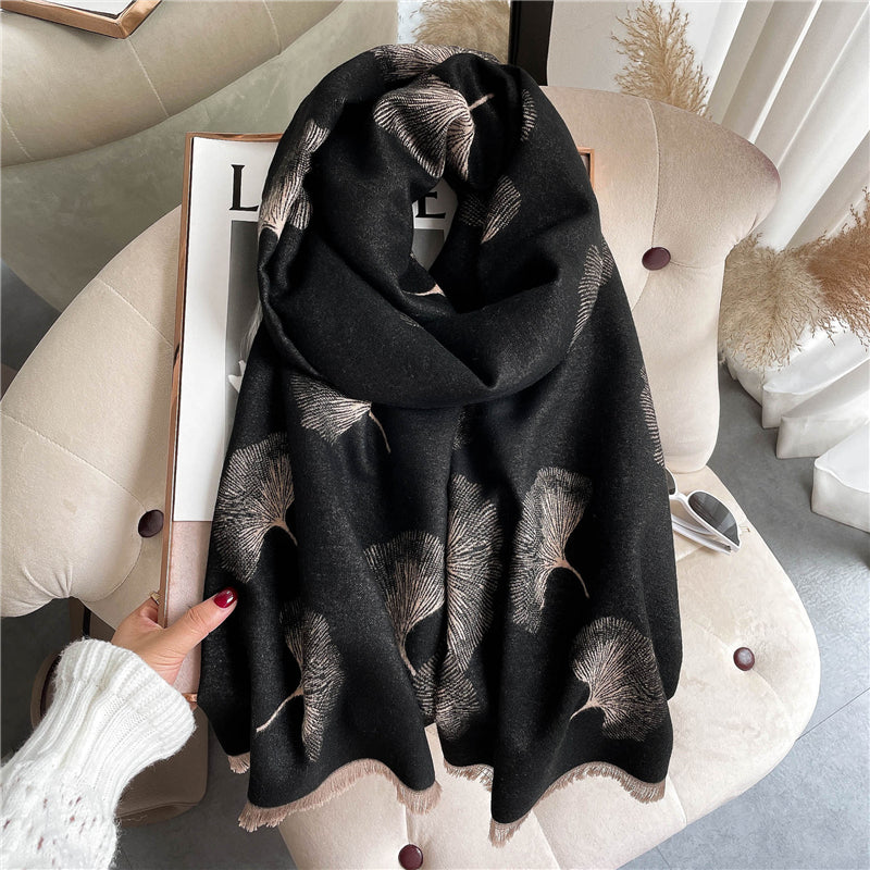 An oblong scarf with a gingko leaves pattern in black and beige colors, displayed on a neutral background.