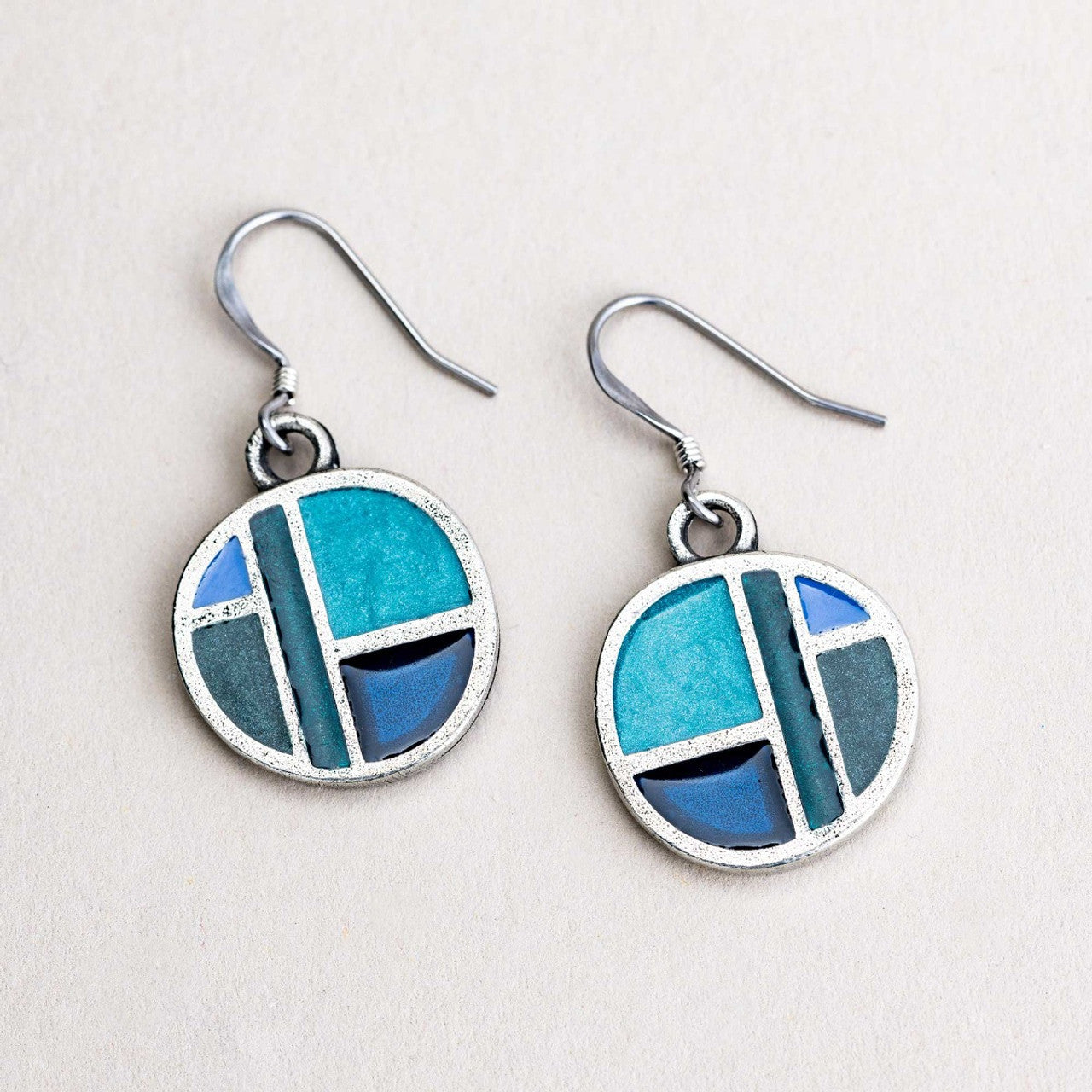 Pair of earrings with blue and silver design on a light gray background