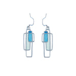 A pair of pewter earrings with a geometric design featuring blue and white colors, attached to silver hooks.