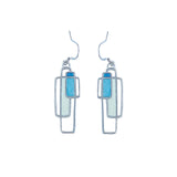 A pair of pewter earrings with a geometric design featuring blue and white colors, attached to silver hooks.