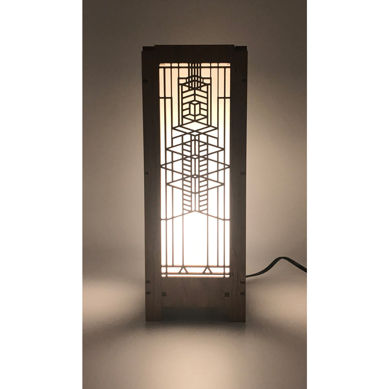 A rectangular lightbox lamp with a design that resembles a window from the Robie House, illuminated by a bulb.
