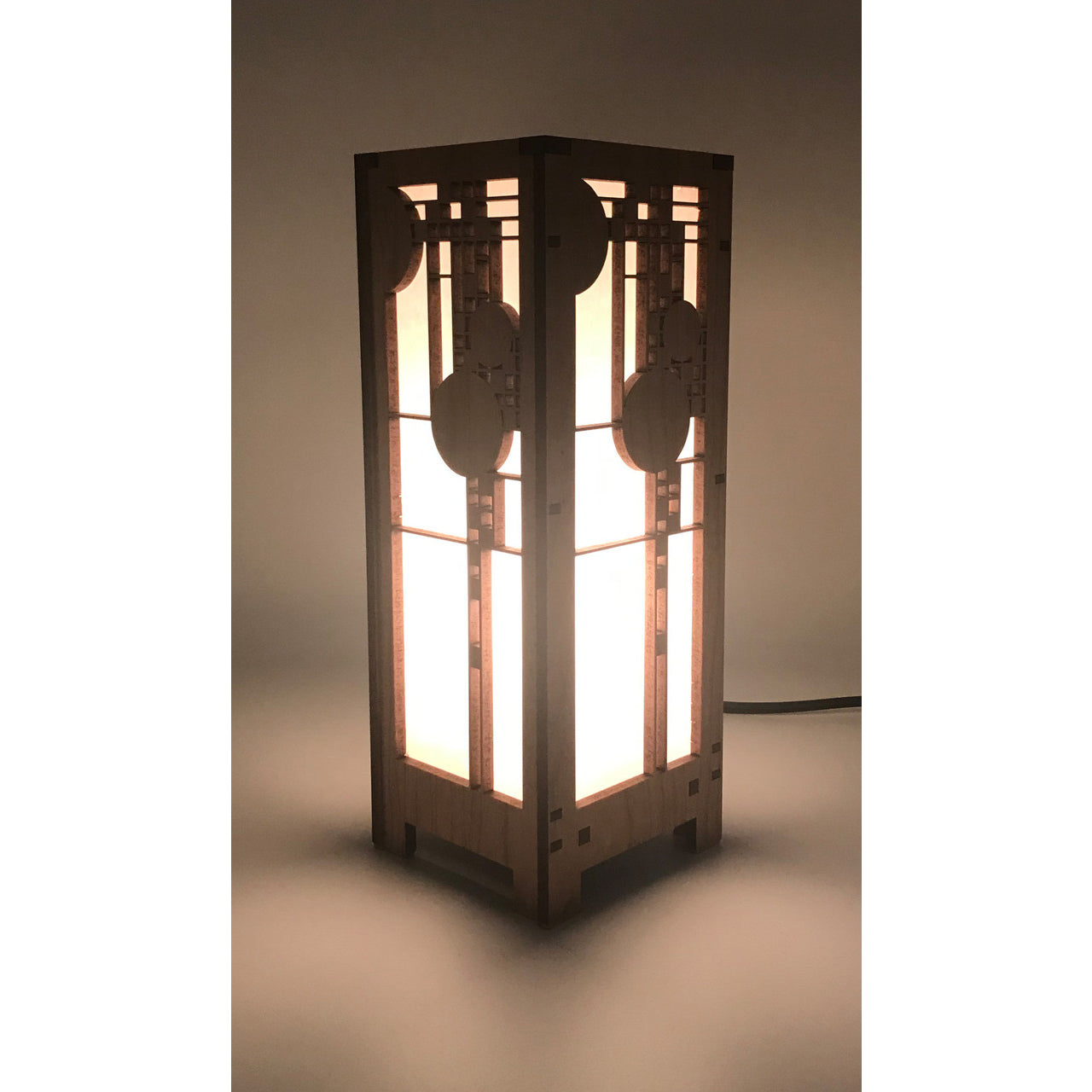 A mini lightbox lamp with geometric art glass window designs, made of cherry veneered MDF and shoji paper, with an illuminated candelabra base.