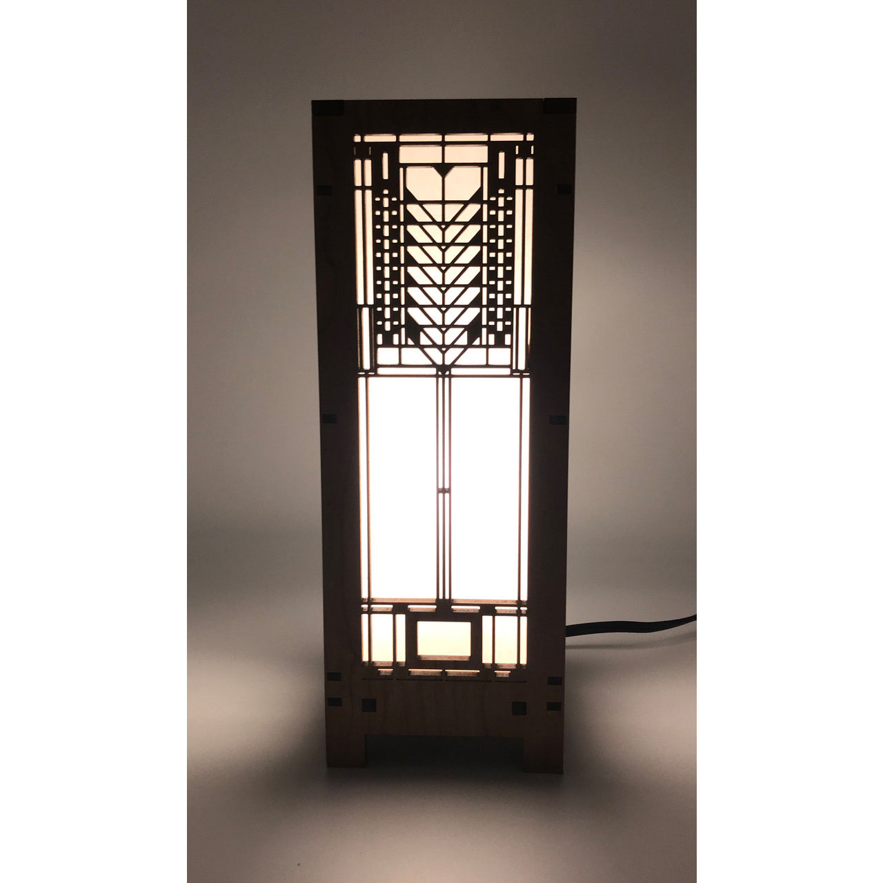 A mini lightbox lamp with a geometric Tree of Life design illuminated from within, set on a dark background.