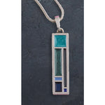 Silver pendant with green and blue inlay on a dark textured background