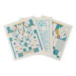 Three white dish cloths with blue and yellow waterlily designs and geometric patterns.