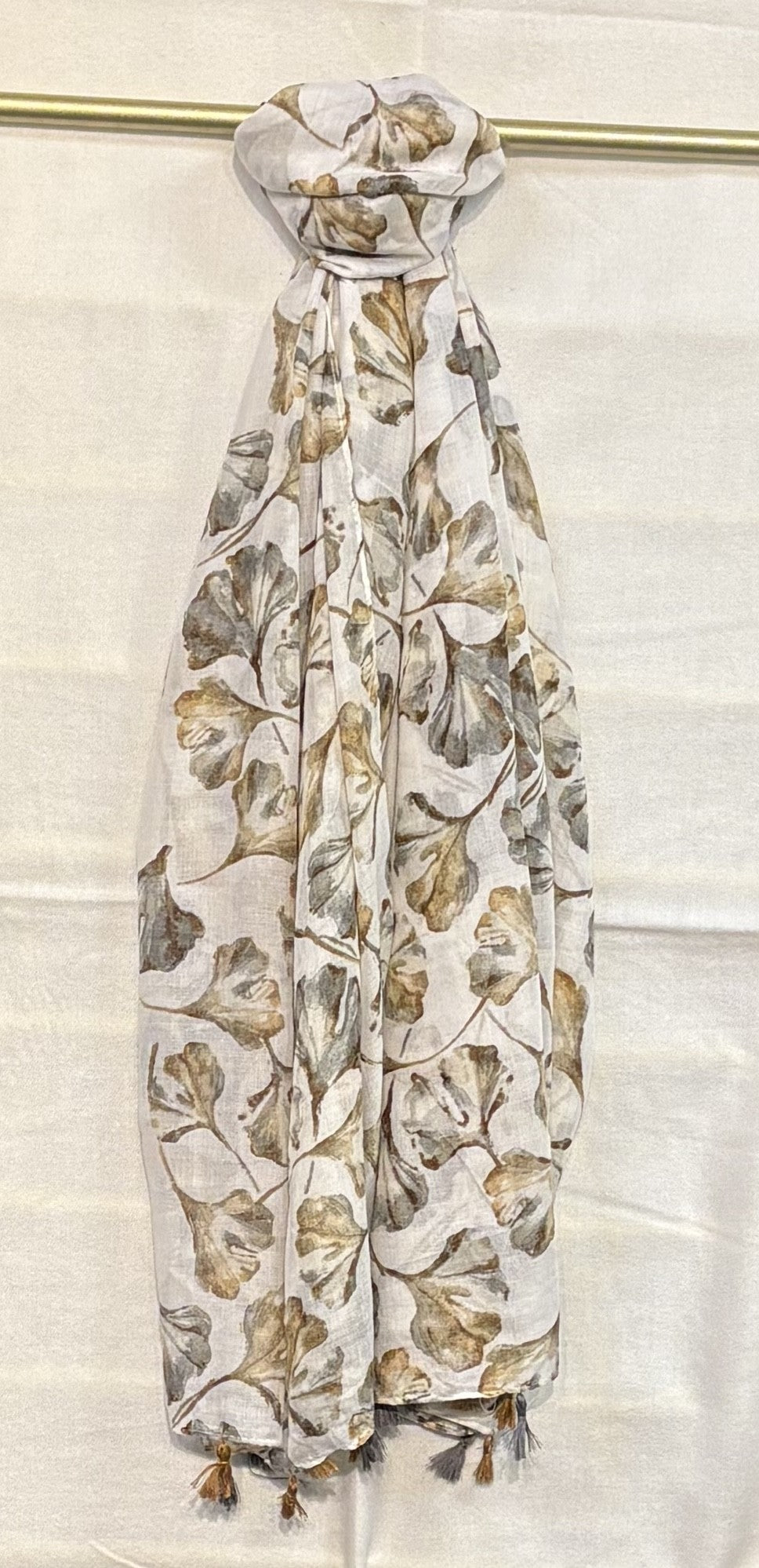 Floral patterned scarf draped over a gold rod on a white background