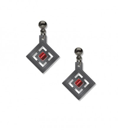 A pair of earrings featuring a geometric design with a red bead in the center, plated in hematite, on a white background.