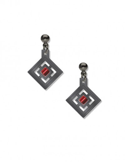 A pair of earrings featuring a geometric design with a red bead in the center, plated in hematite, on a white background.